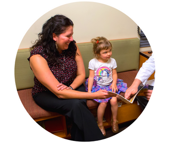 Executive Director, Kris Hoplin, and her daughter share a book with their doctor