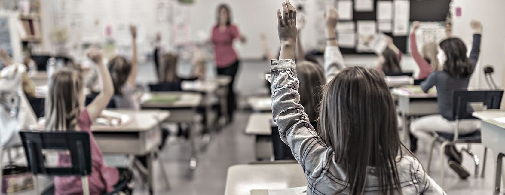 Children raising hands in classroom