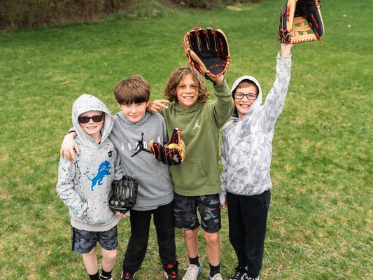 Group of boys holding up baseball mitts.