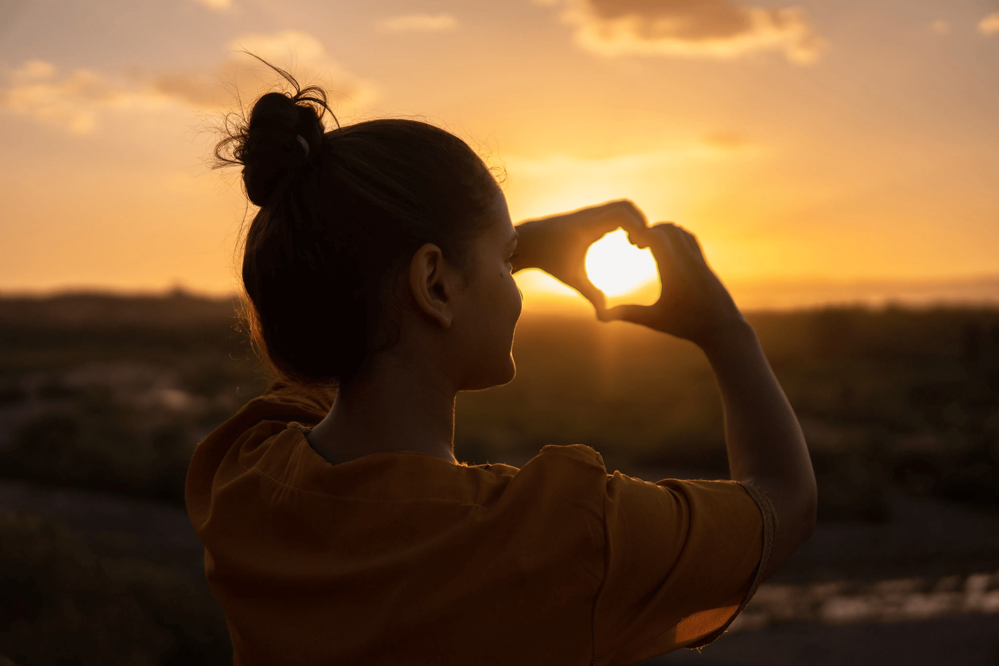 making a heart out of hands in the sun