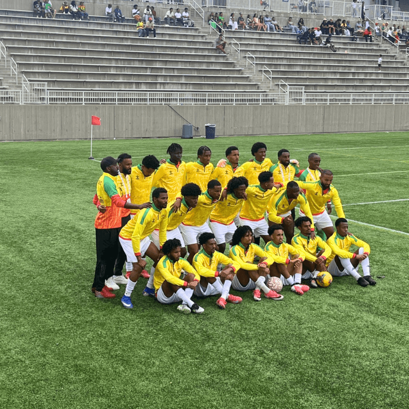 An Ethiopian diaspora soccer team poses together on the field at ESFNA 2026, wearing yellow and green uniforms, TCO Stadium, Eagan, Minnesota