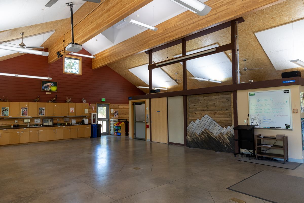 An image taken inside the Red Barn facing the front of the room where there is a mountain mural and screen for the projector.