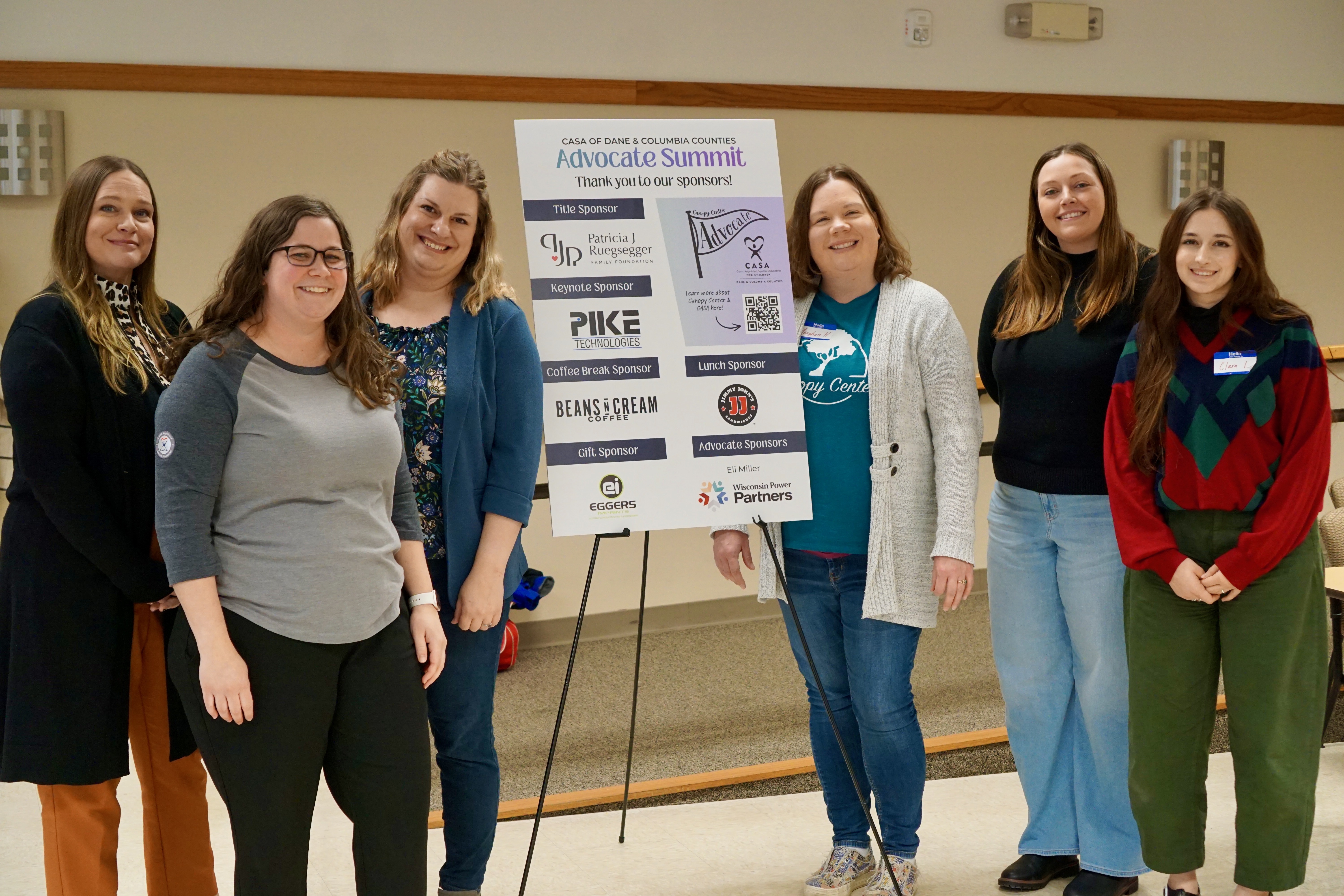 Canopy staff stands in front of a sign thanking our sponsors