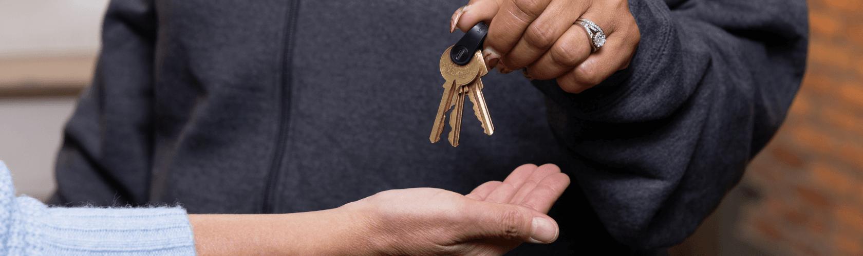 Image shows a person holding a ring of keys out above another person's open palm.