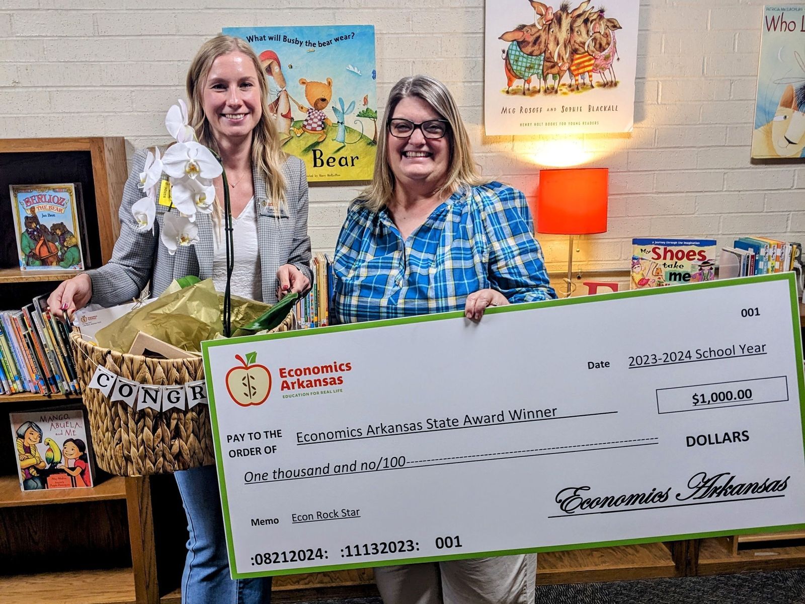 two women holding a large check and basket with award