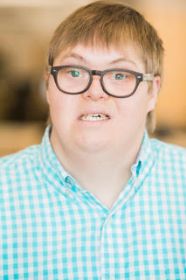 Professional photo of white man with Down syndrome smiling at camera