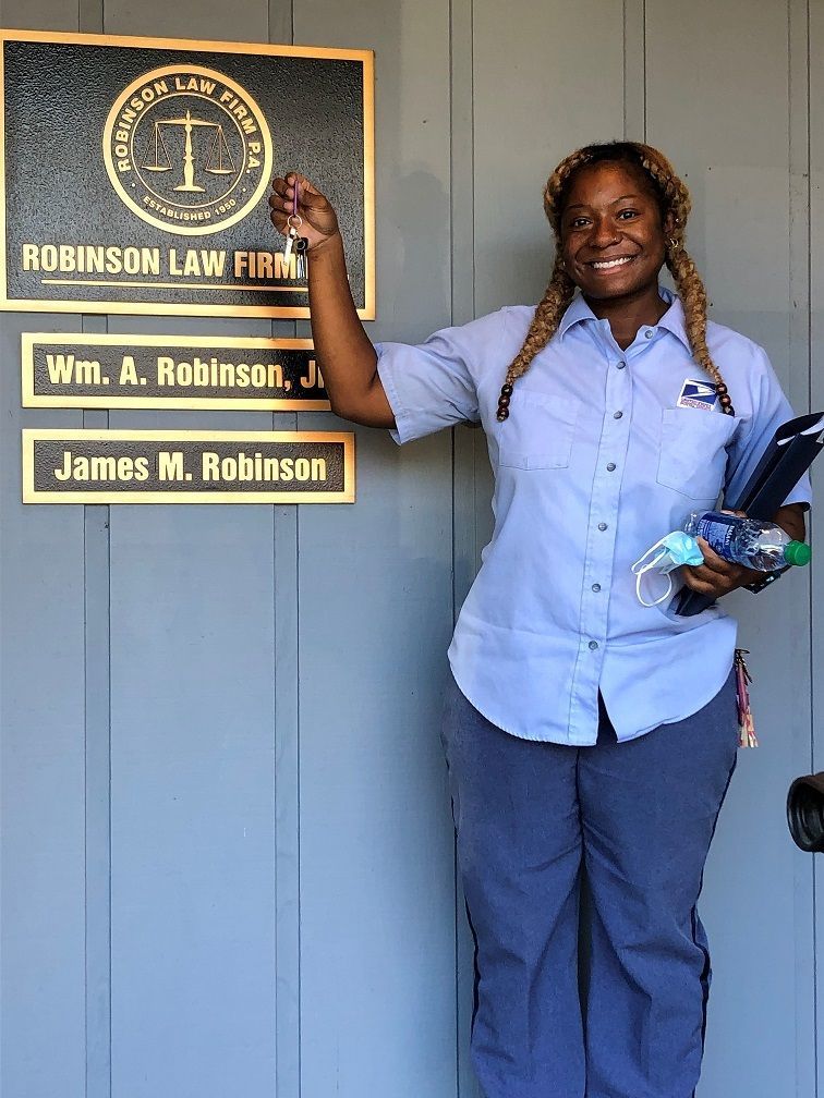 Homeowner Kiara holds up her house keys in front of the law office where her closing occurred 