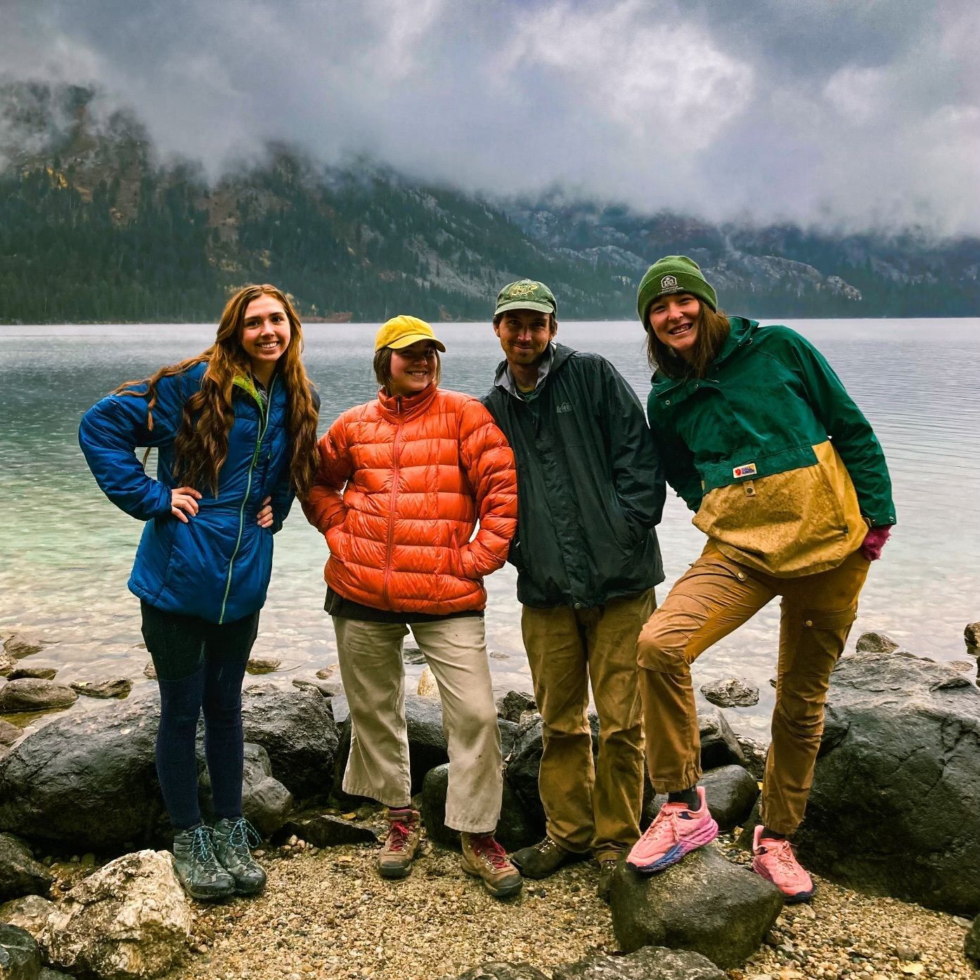 A crew stands beside a lake, smiling at the camera.