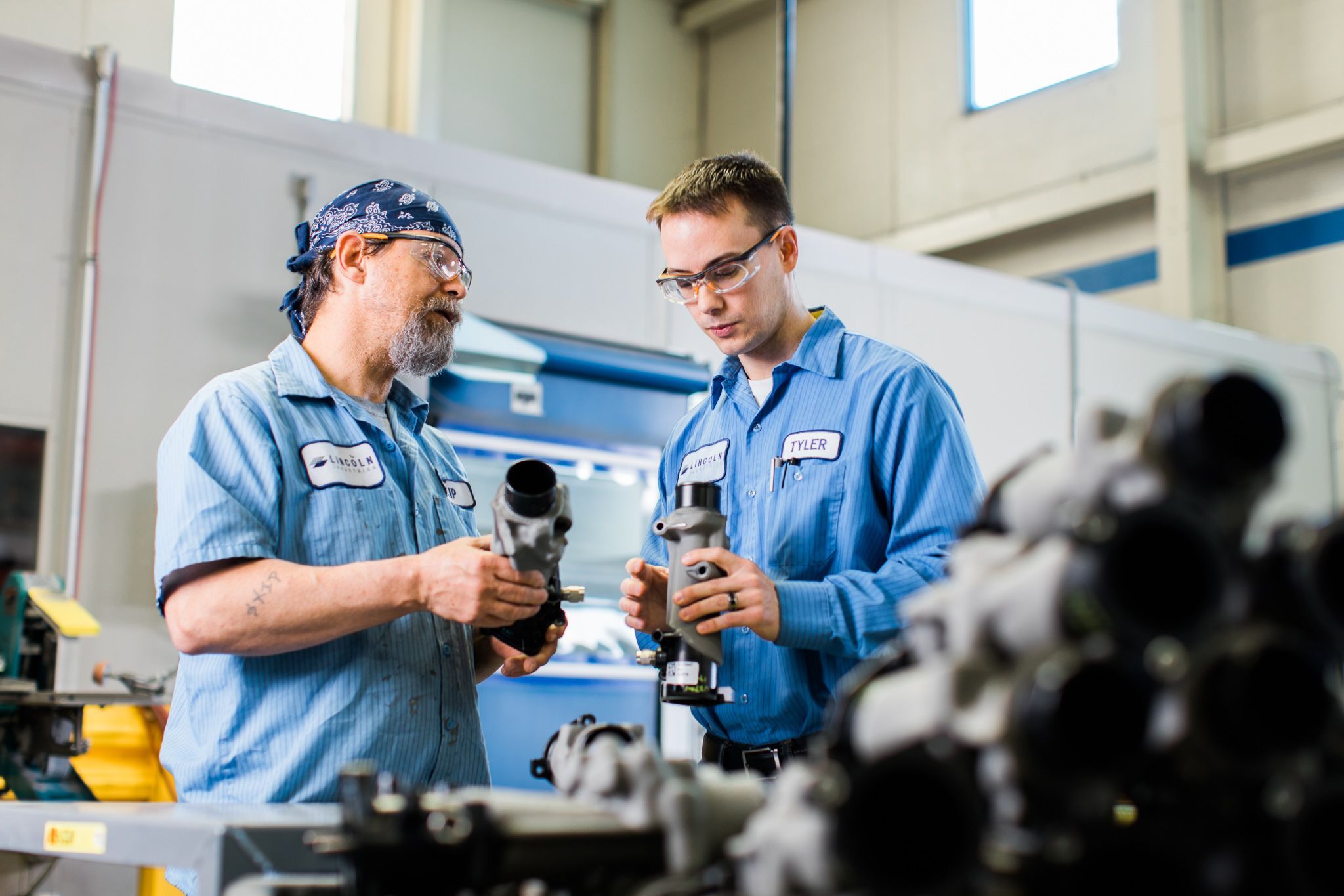 Men in a warehouse inspecting metal parts.