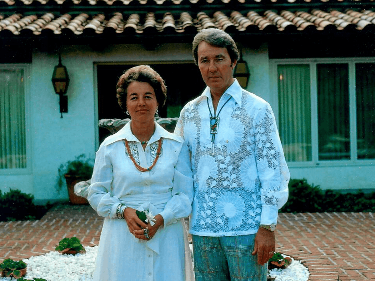 man and woman posing in front of house