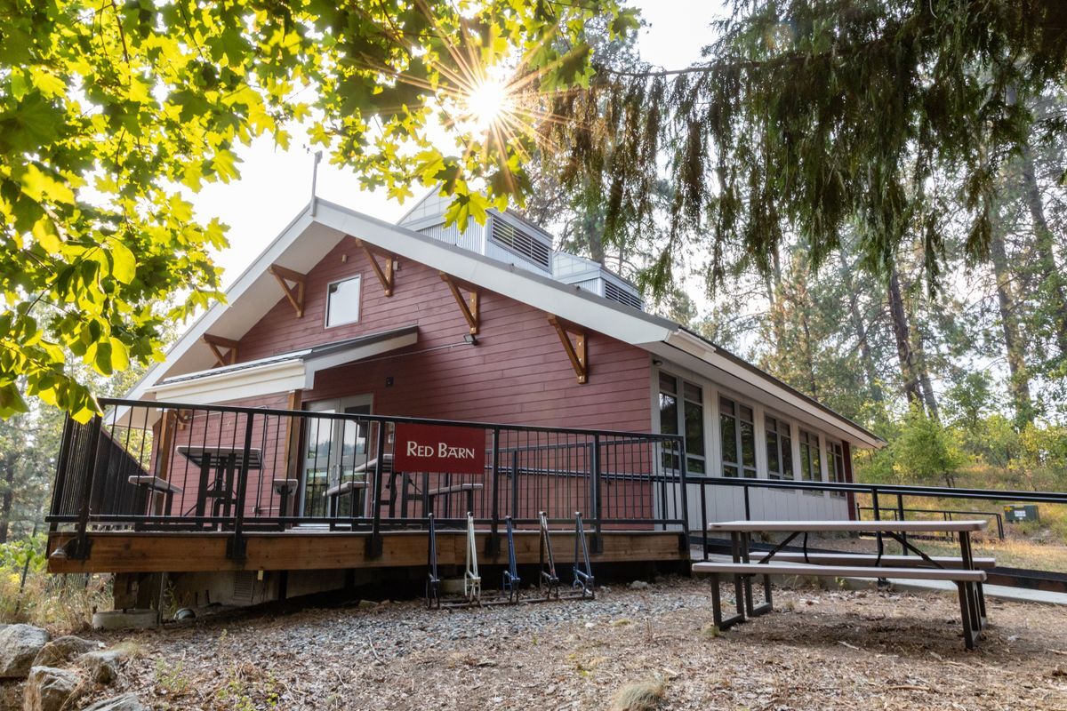 A red building called the Red Barn, a deck with picnic tables with sun rays beaming down.