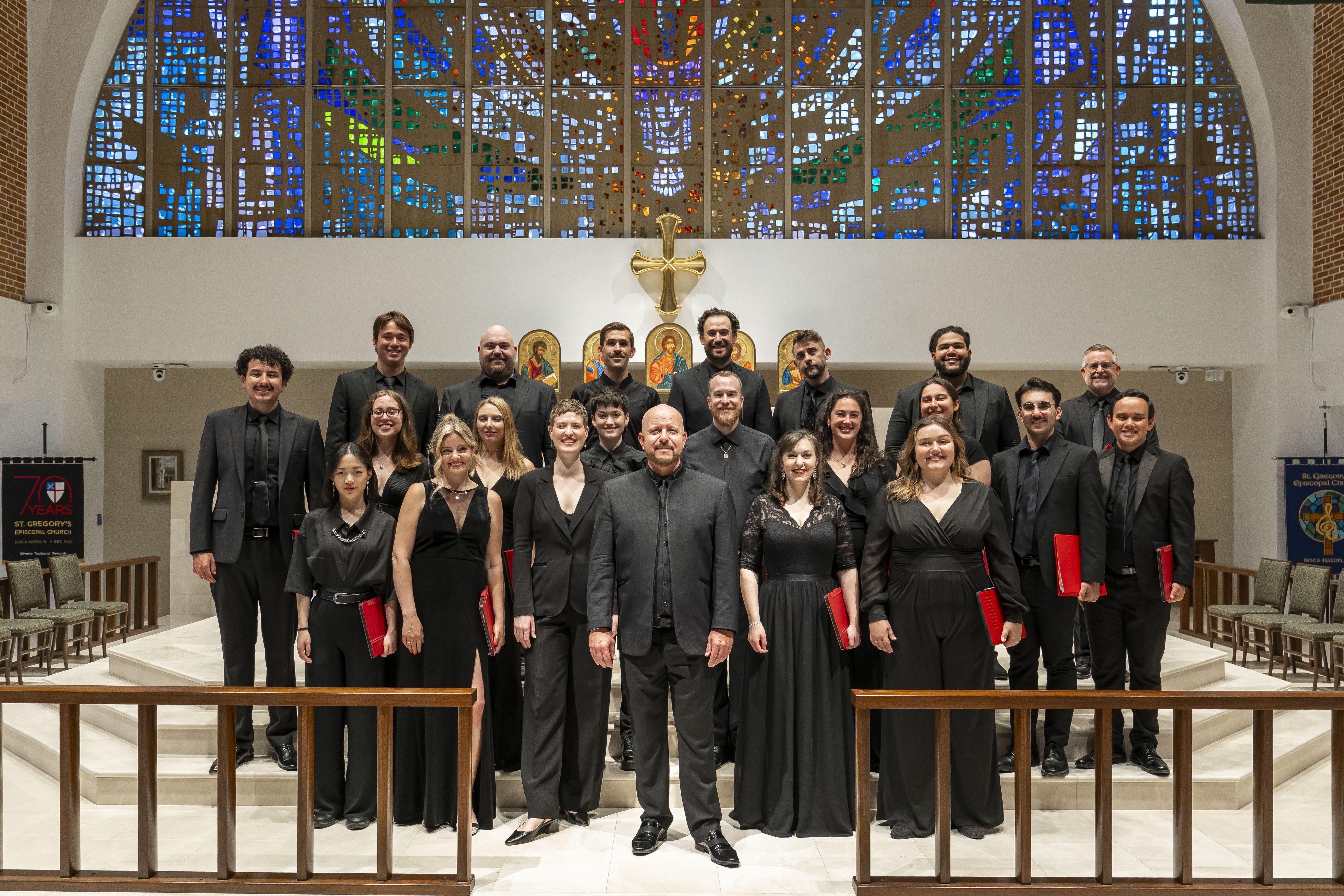 A photo of the Seraphic Fire ensemble and conductors outside with trees in the background.