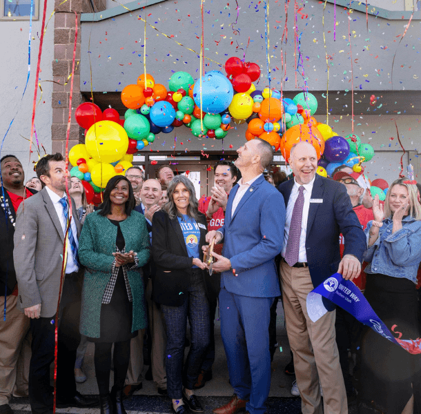 a photo from our ribbon cutting that shows confetti and a group of people excited after cutting the ribbon