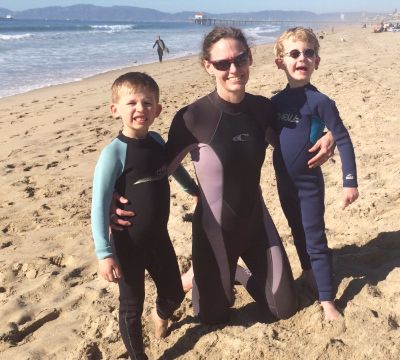 Caroline and her two boys at the beach in wetsuits
