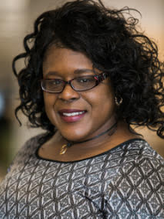 Professional photo of black woman with curly hair and glasses smiling