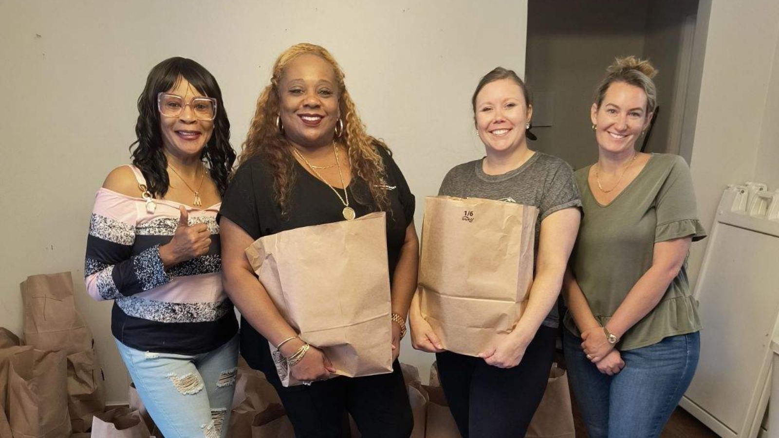Four volunteers hold paper bags of groceries at the food pantry.