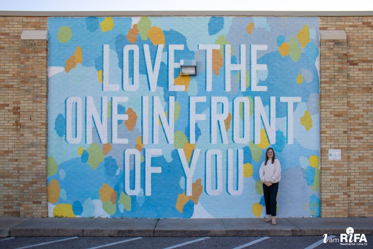 Denice in front of the "Love the one in front of you" wall mural