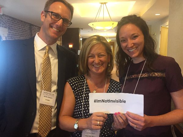 Photo of Mark Dunning, Carol Brill and Krista Vasi holding a sign that reads #ImNotInvisible