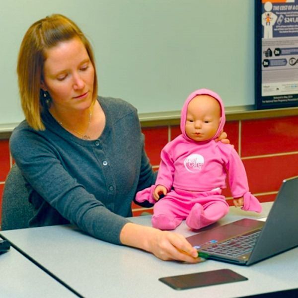 a teacher demonstrating how to care for a RealCare baby.