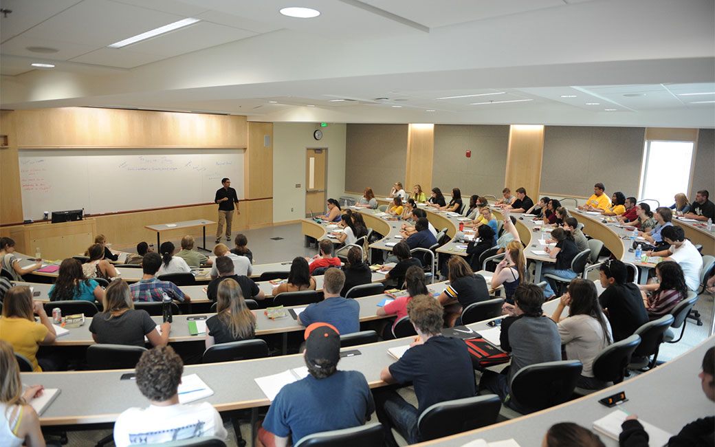 Students seated facing whiteboard in semi circle style lecture hall