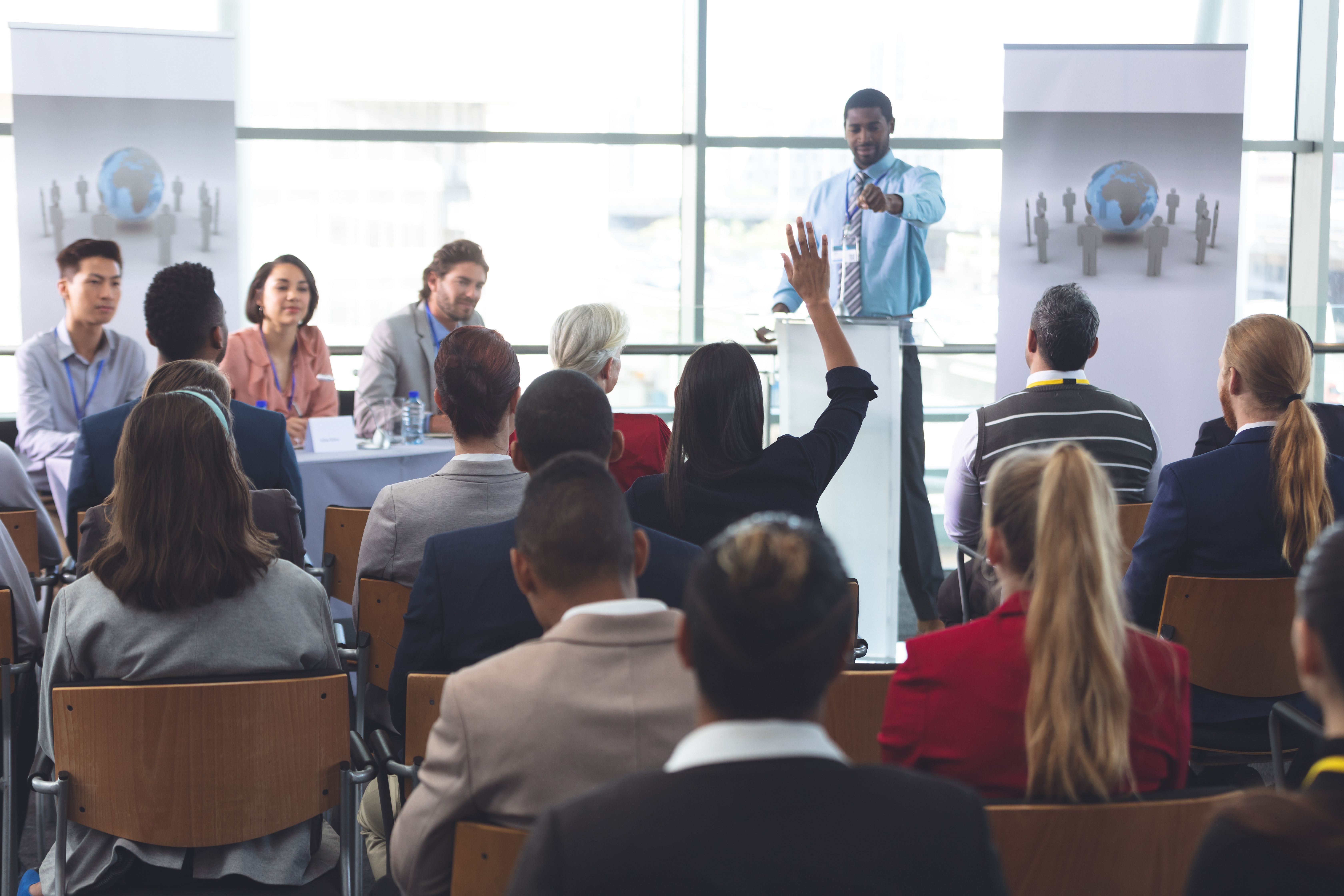 Diverse people at a learning event in which the speaker calls on someone raising their hand