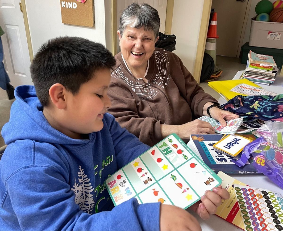 Male student and a Felician Sister laughing and practicing with flashcards.