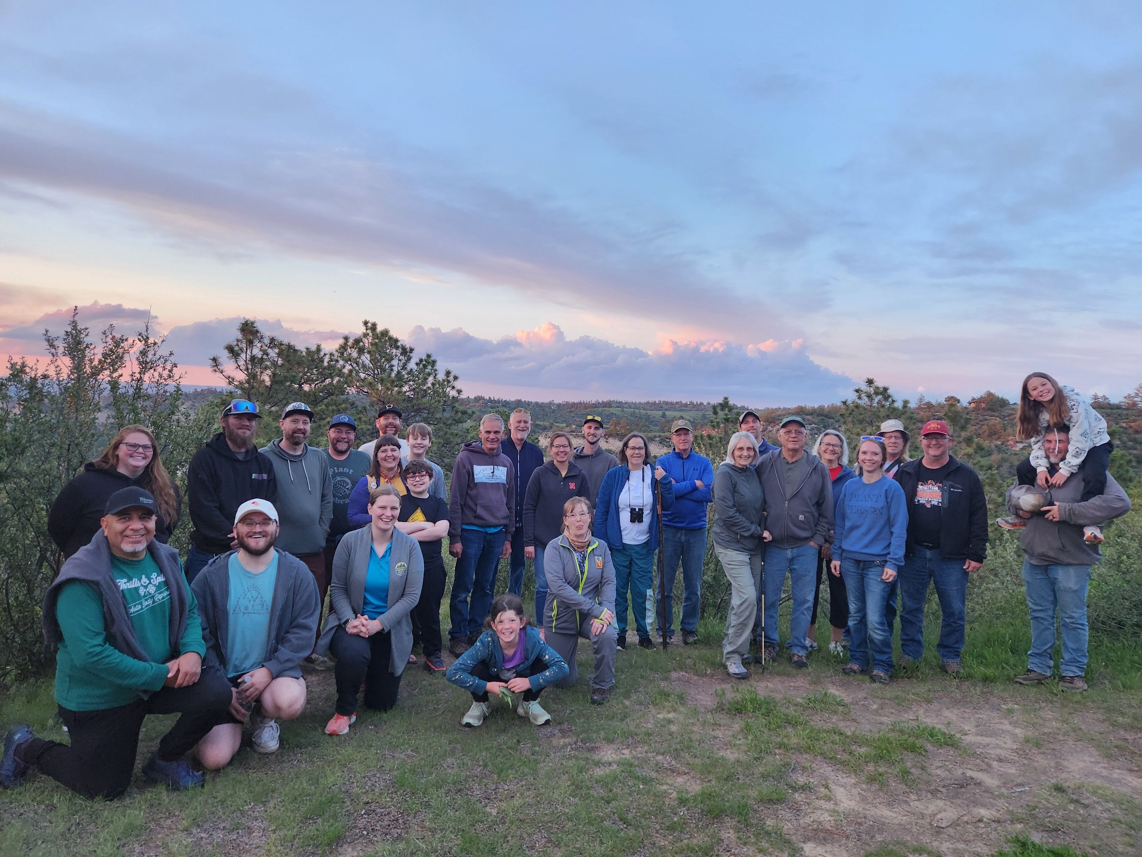 A group of hikers gathered at Wildcat Hills with a subtle sunset in the background. 