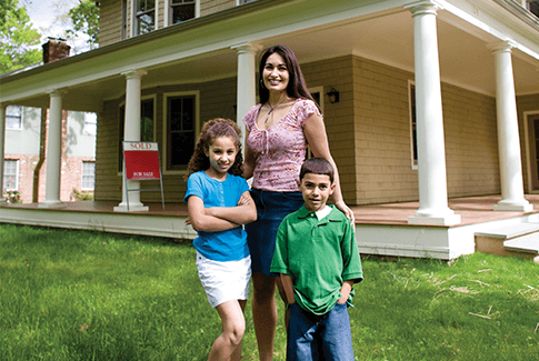 Homeowner and two children standing in the yard in front of their house