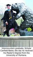 Intermountain graduate, Schylar Canfield-Baber smiling by bear statue.