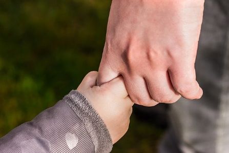 Child holding the finger of an adult