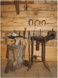 A rustic blacksmithing workshop with tools, an anvil, and a grinding wheel.