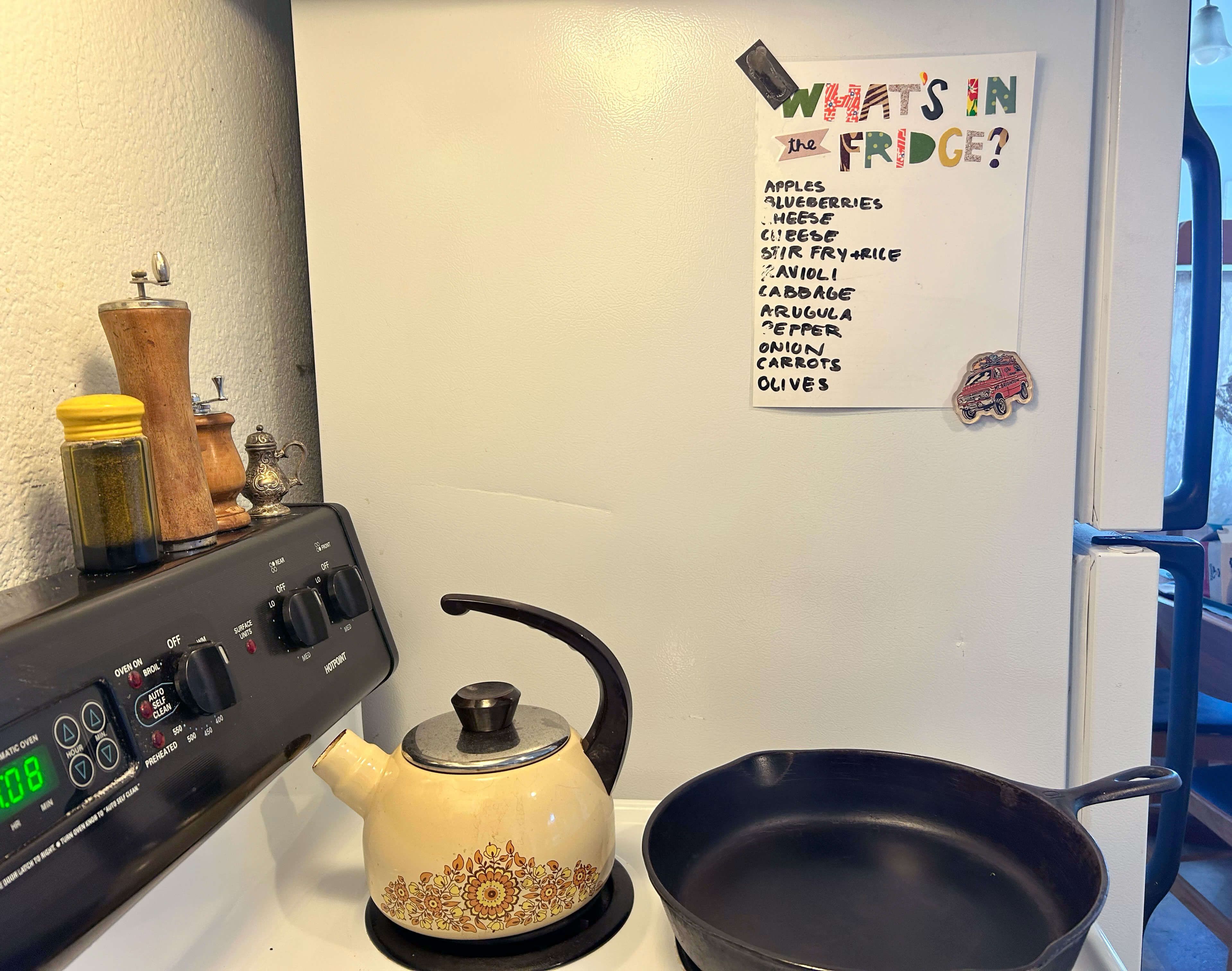 On the side of a fridge is a piece of paper "What's in the Fridge?" with a list of perishables. 