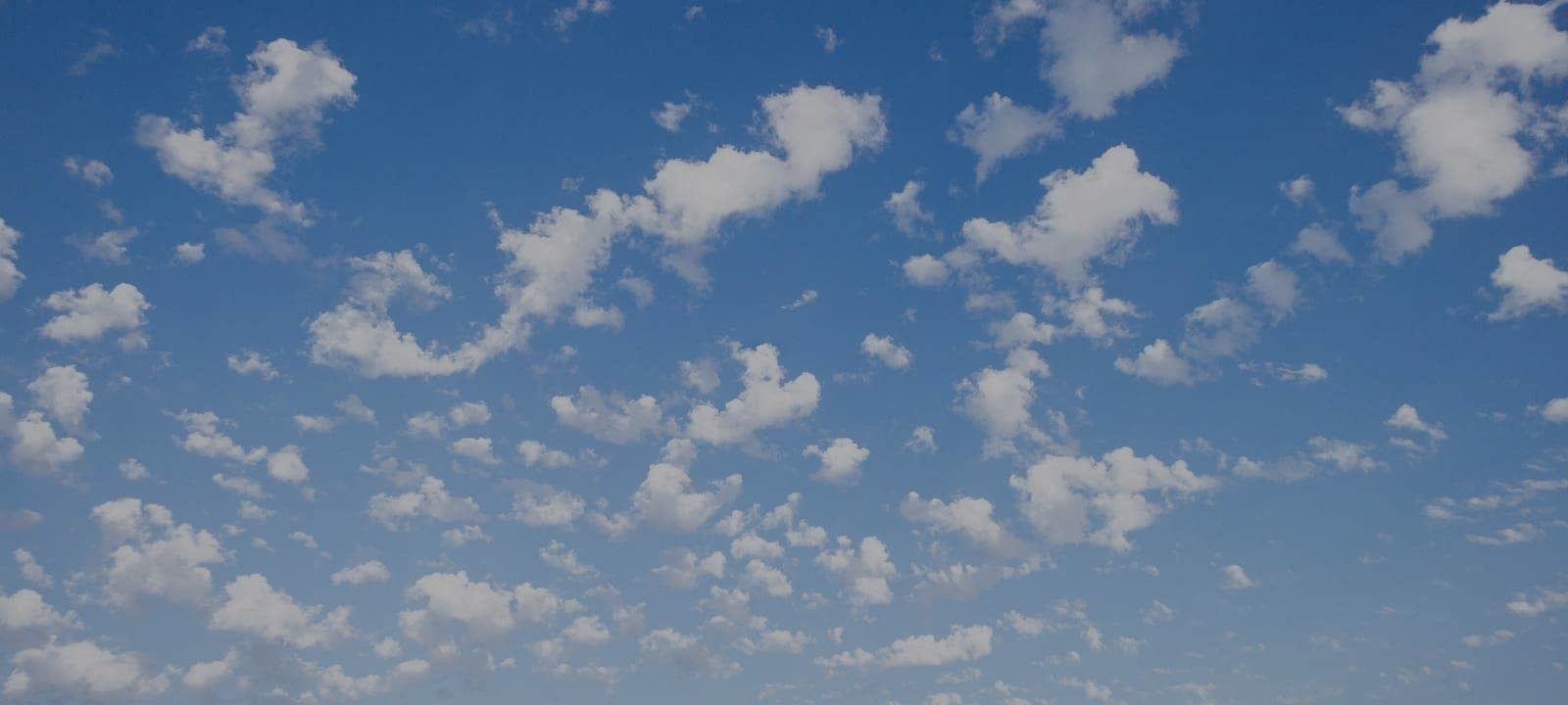 Photo of a blue sky with small puffy clouds disbursed across it.