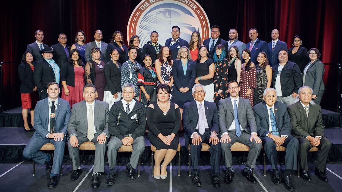 The group of 2017 40 Under 40 award winners dressed in formal attire stand on a stage.