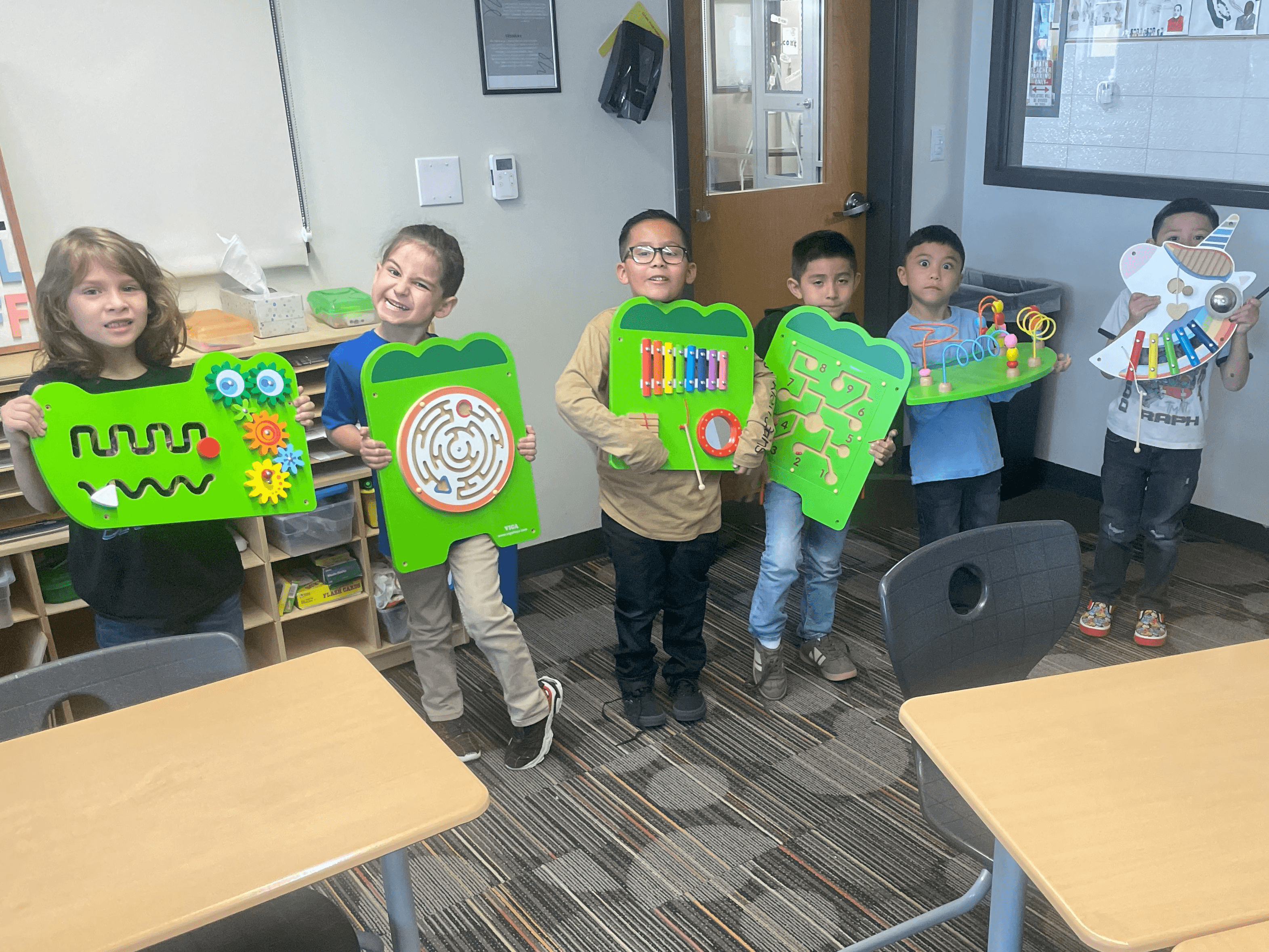 A group of young students proudly hold colorful learning boards created through a Marchi Mini Grant project, highlighting the role of social-emotional learning in the classroom.