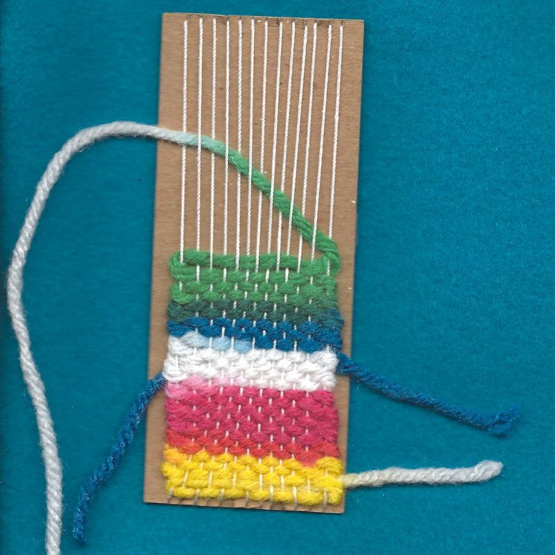 A small cardboard loom with a half-finished woven bookmark on it