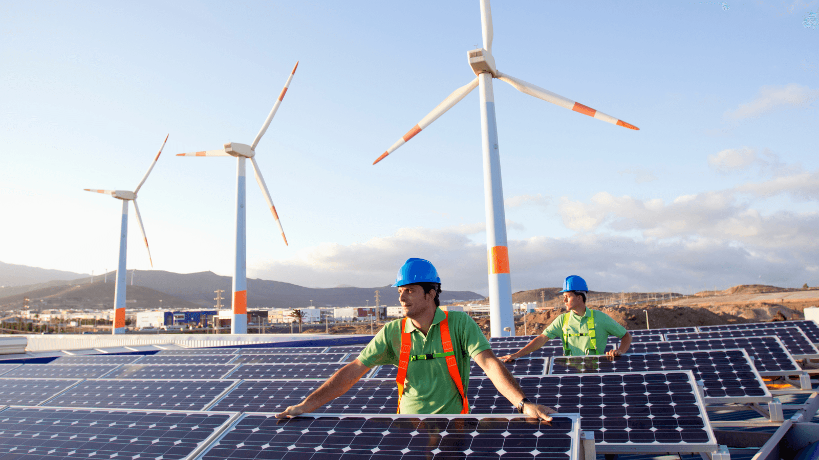 Workers standing by solar panels and wind mills 