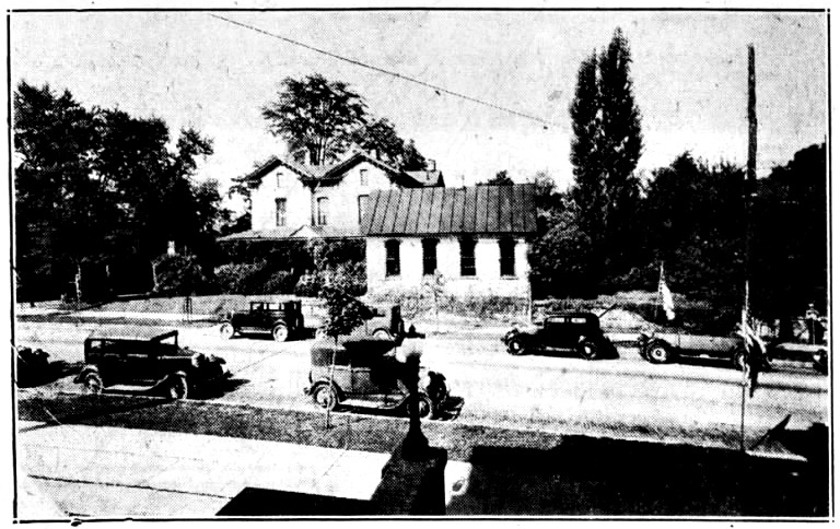 Black and white image of a house, street, and cars in 1936