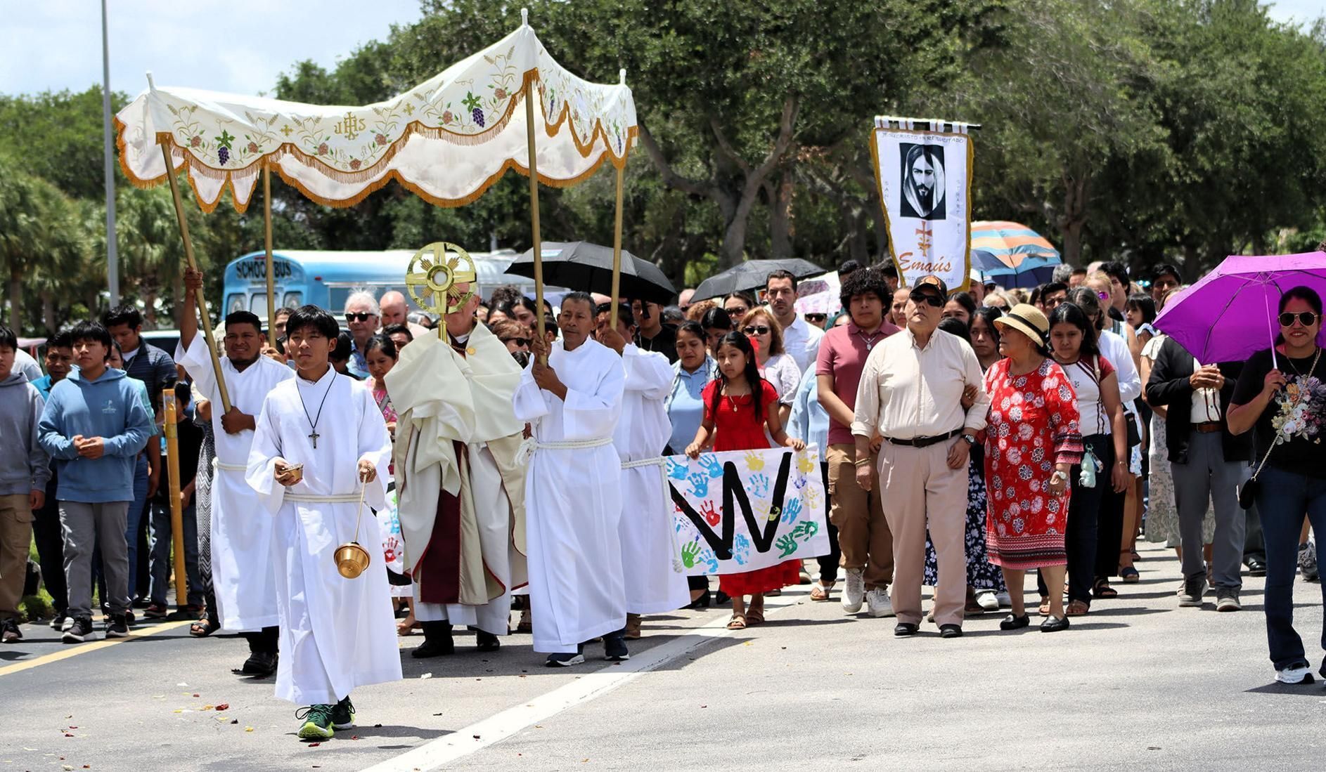 Father Noel McGrath, pastor of St. Joseph in Stuart, leads his diverse flock, with a large Spanish population, around the church grounds and through the neighborhood with Jesus in the Eucharist.
