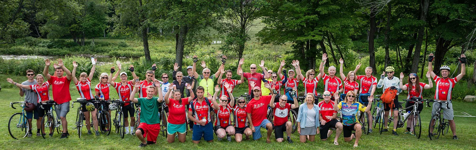 A line of people in red shirts are standing next to bicycles and cheering