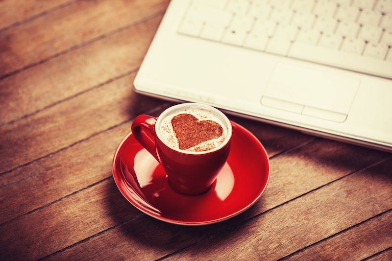 Cappuccino with a heart made of cinnamon and a laptop