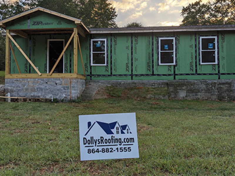 A Dolly's Roofing sign adorns the front lawn of a Pickens County Habitat for Humanity house under construction