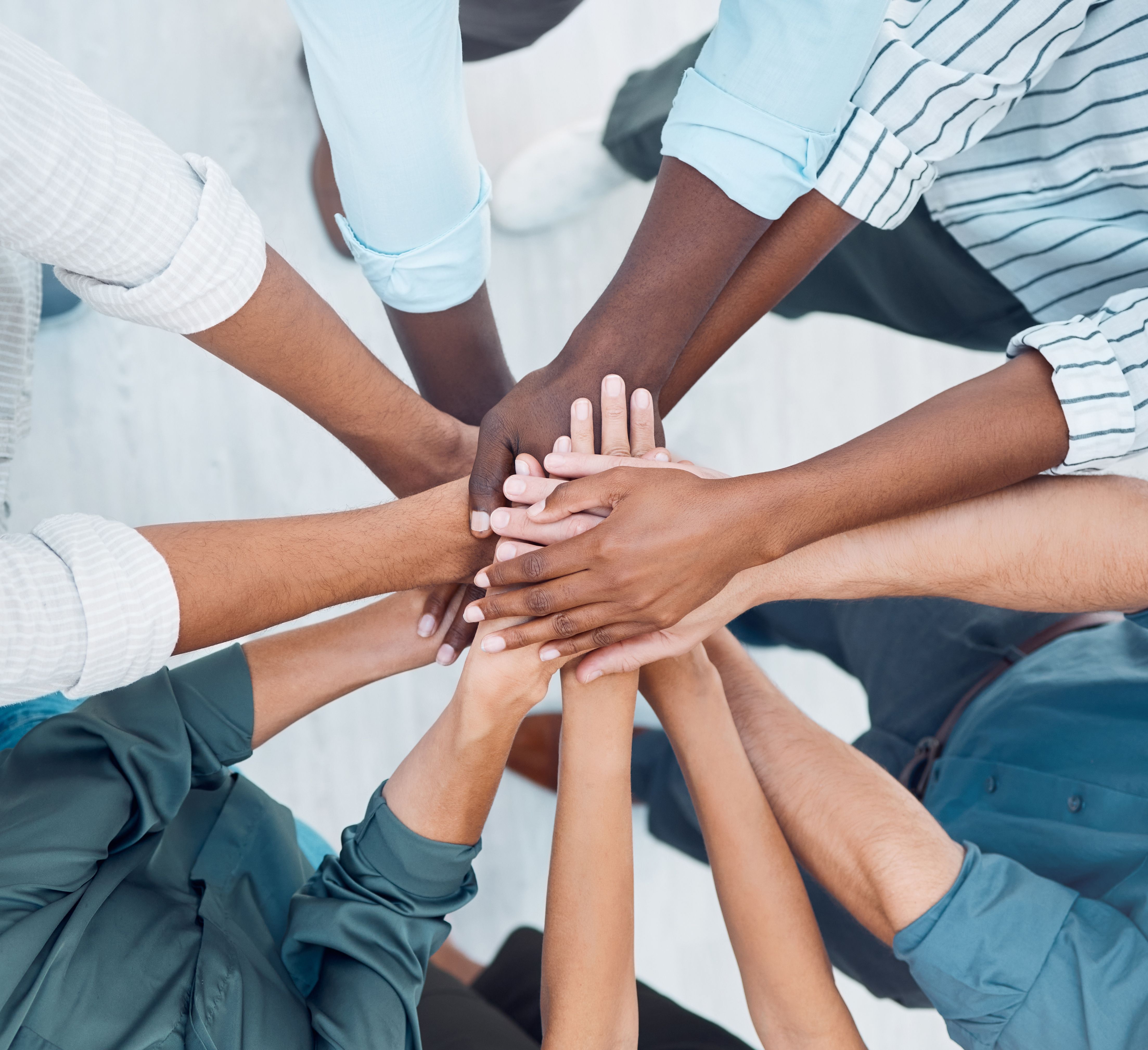 Diverse group of people holding their hands together, representing teamwork and collaboration