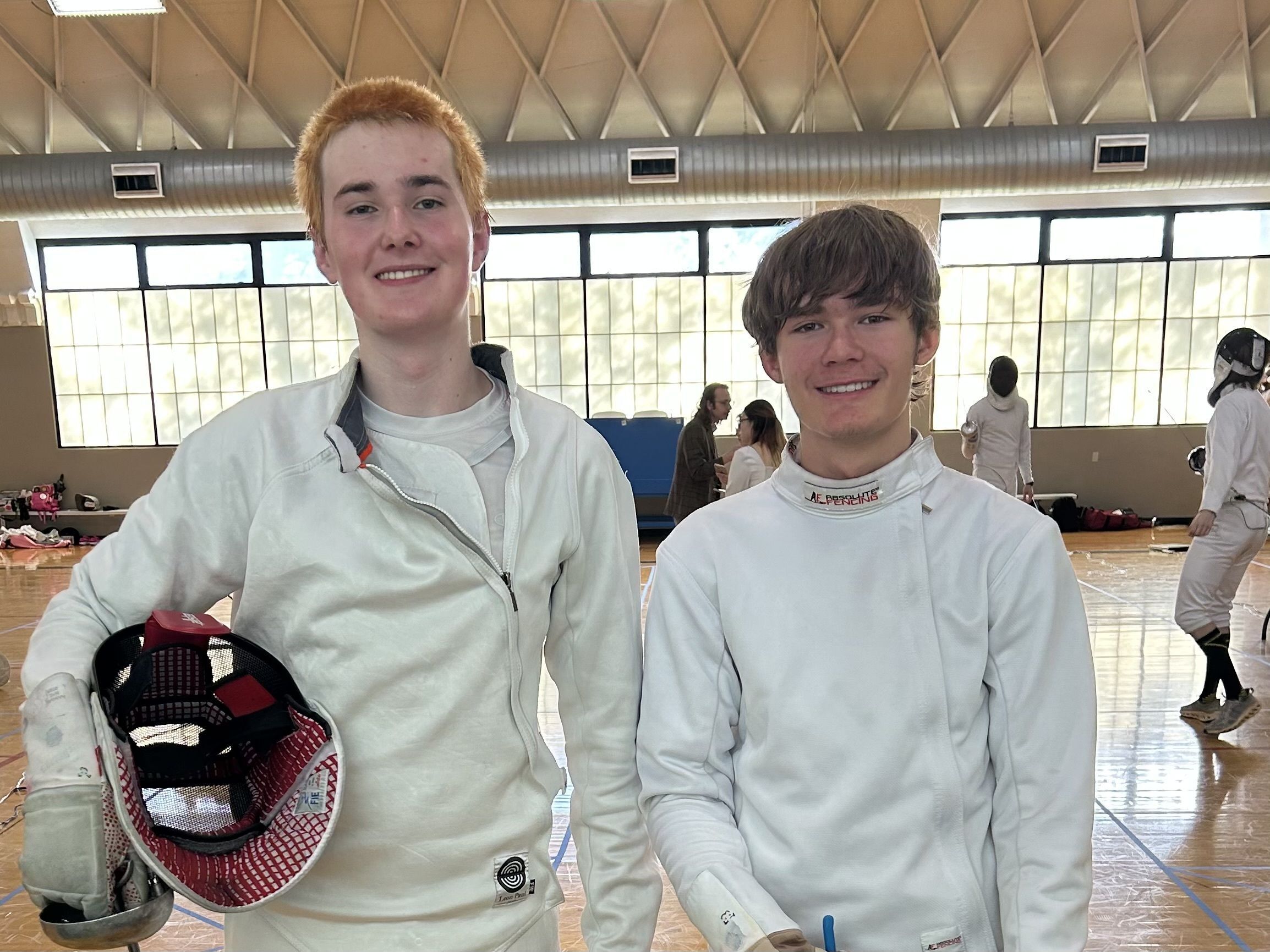 Two fencers smile at the camera