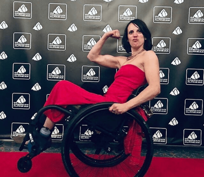White Woman in a red dress on a wheel chair on a red carpet