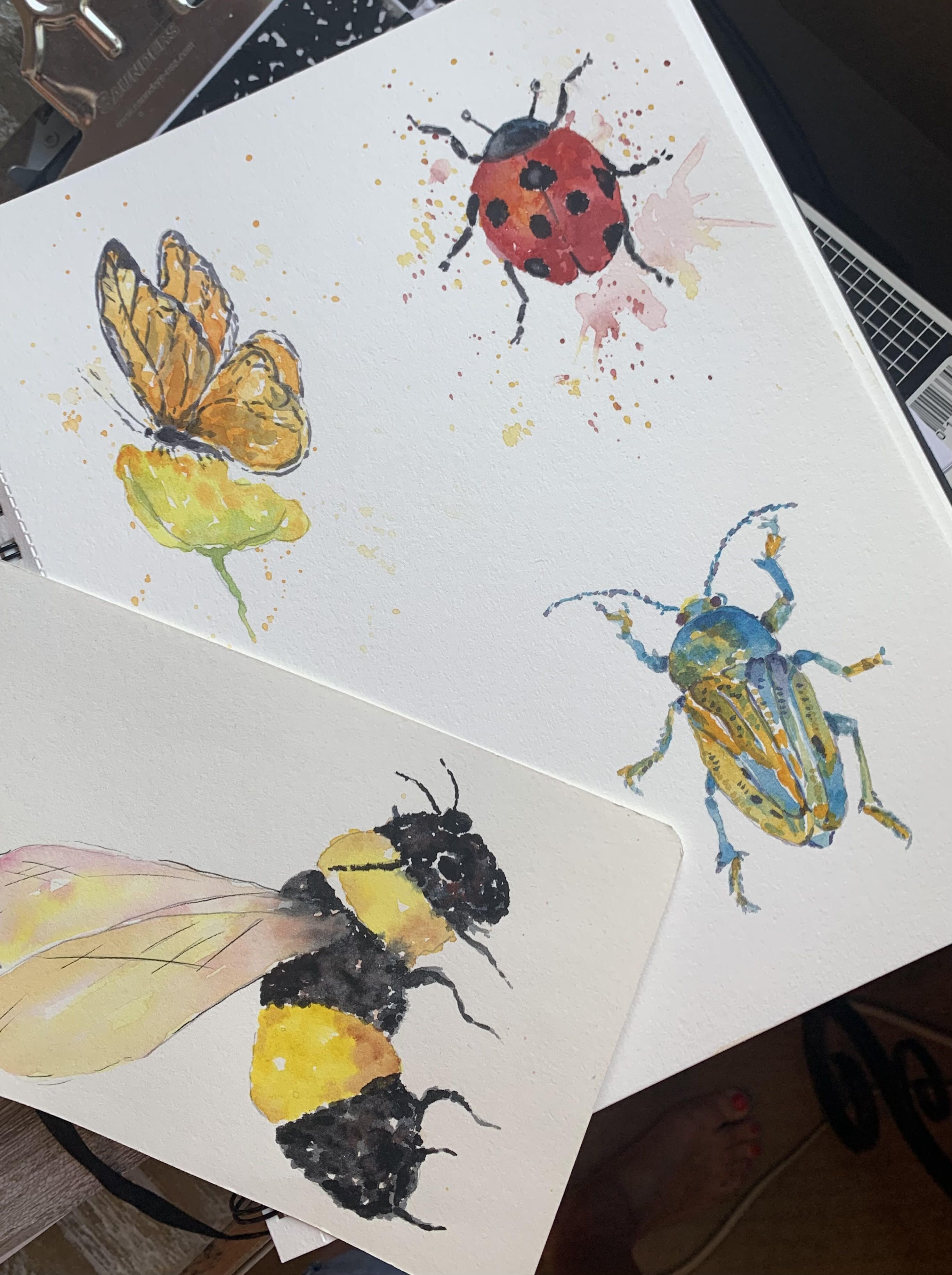 Water color painting of a bee that is striped yellow and black in mid flight along with an orange butterfly, red lady bug and beetle.