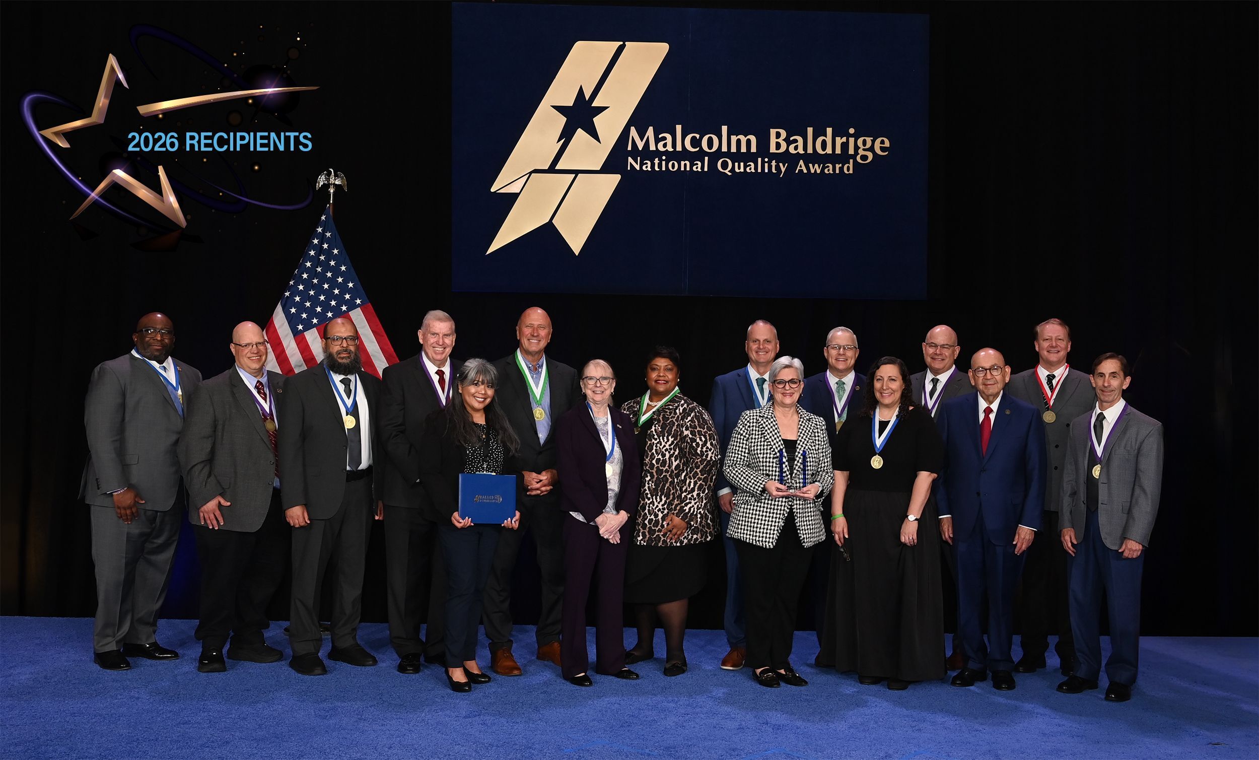 Group photo of the 2026 Foundation Leadership Award Recipients on stage with am american flag behind them. 