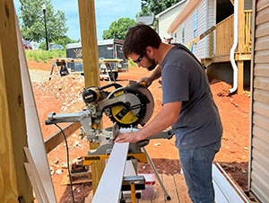 Volunteer using a miter saw to cut trim board