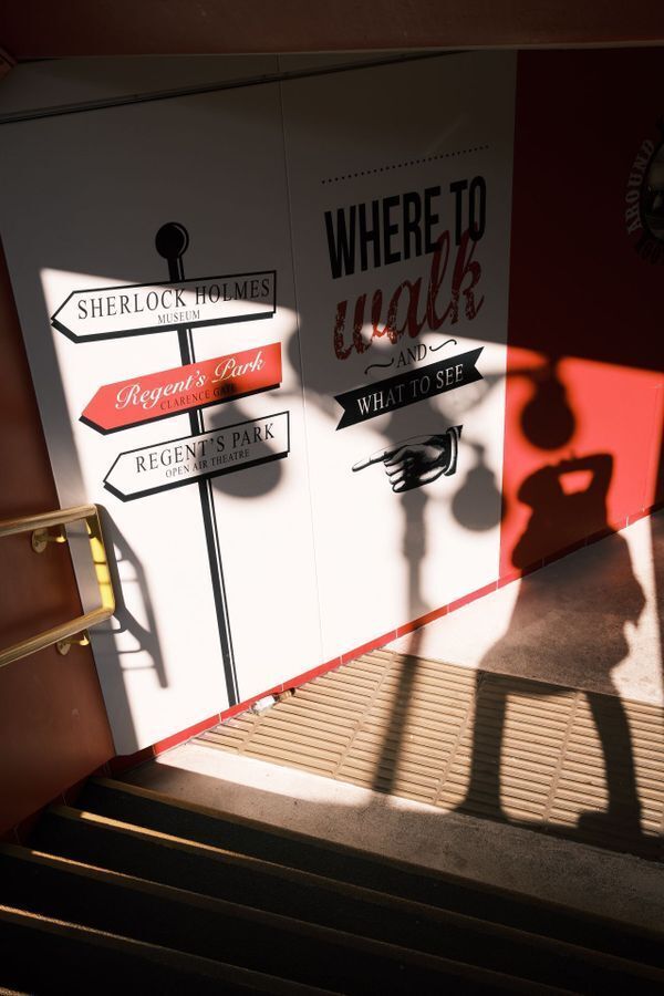 Wall graphics design with vintage signpost graphics reading "Where to Walk and What to See" near the Sherlock Holmes Museum entrance.