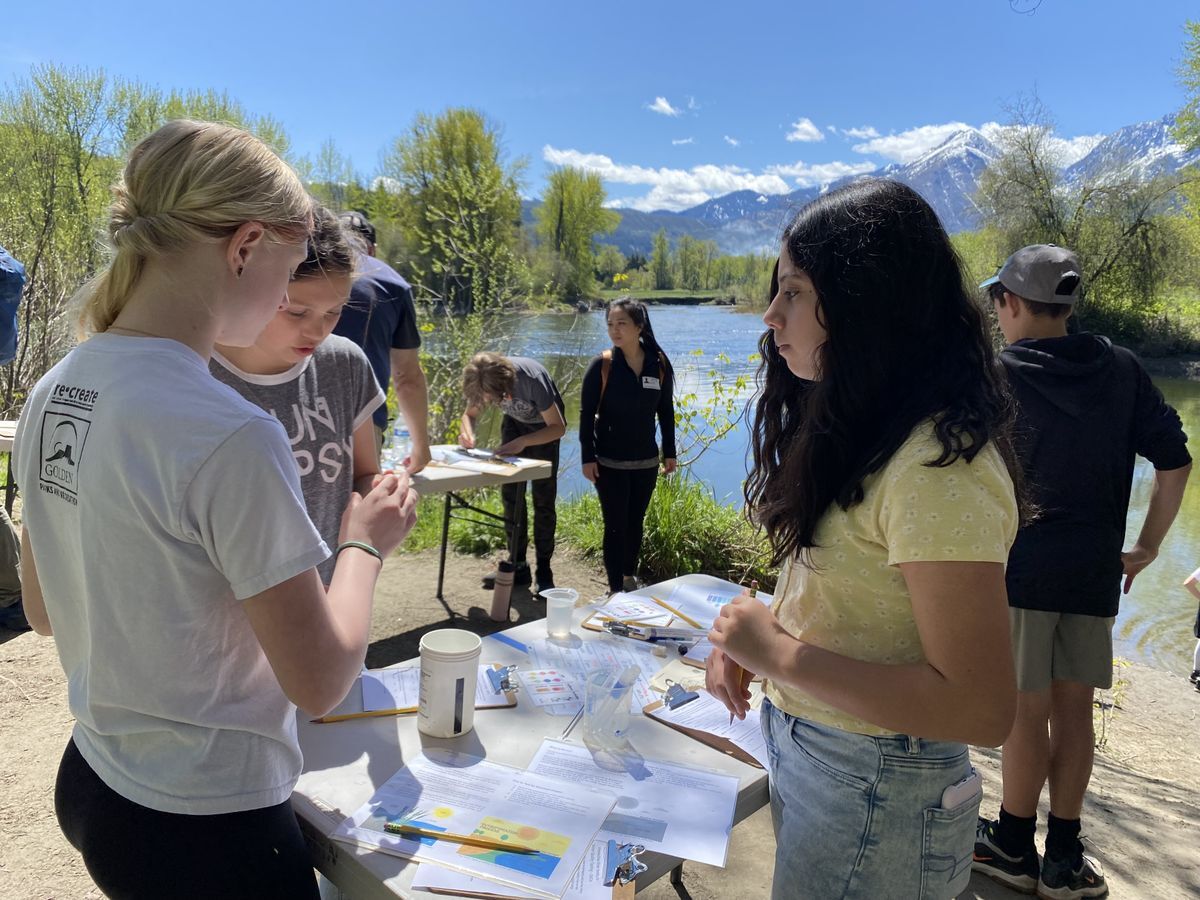 A group of students doing a water experiment on the banks of the river.